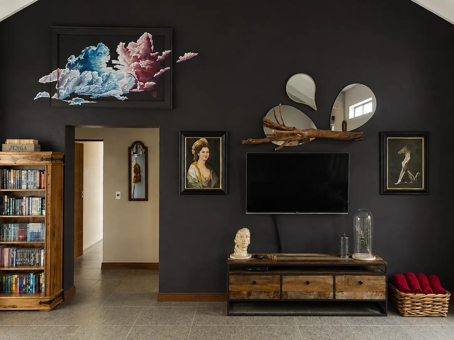 Paintings and artworks displayed on the dark lounge wall in Flute Cottage at Klawerjas