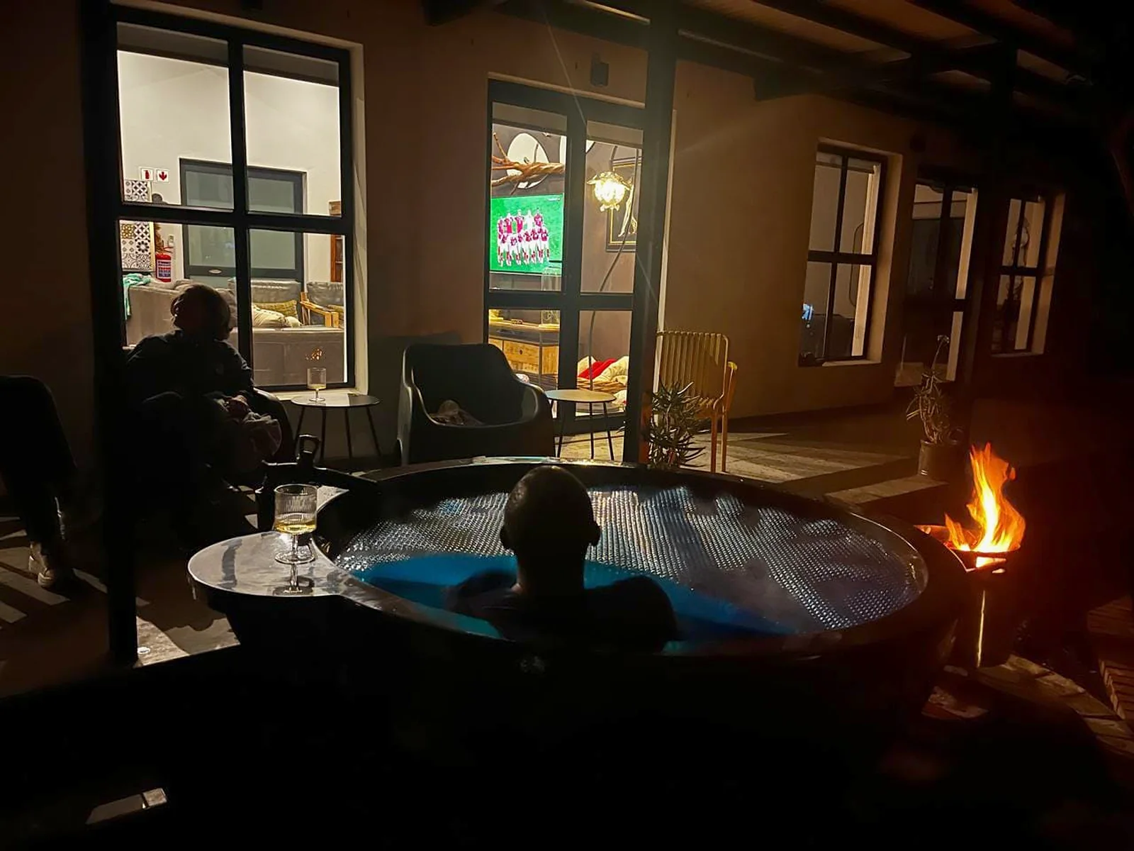 Guests relaxing in the Tickle Tub beside Flute Cottage on a firelit evening