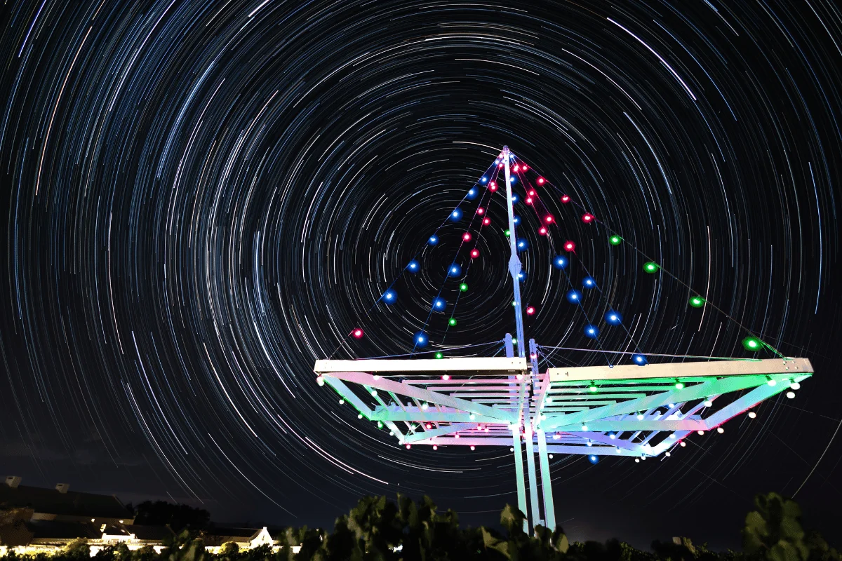 Star trails circling above the illuminated vineyard pergola at Klawerjas